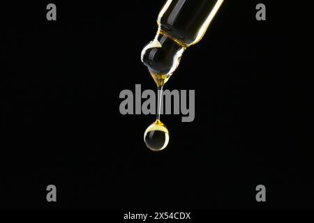 Tropfende Tinktur von Pipette auf schwarzem Hintergrund, Nahaufnahme. Leerzeichen für Text Stockfoto