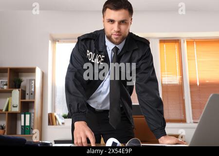 Männlicher Polizist, der im Büro arbeitet Stockfoto