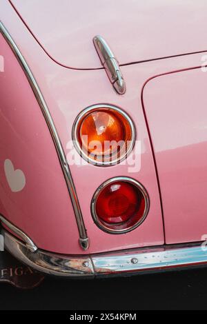 Rosafarbener Nissan Figaro mit Ohren und Schleife am Lenkrad in den Straßen Londons Stockfoto