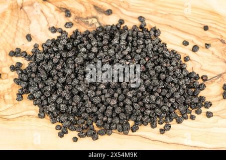 Schwarze Schokolade (Aronia melanocarpa, Photinia melanocarpa), getrocknete Apfelbeeren auf einem Holzbrett Stockfoto