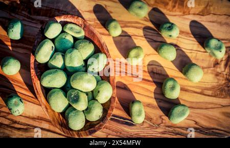 Wasabi, japanischer Meerrettich (Eutrema japonica, Wasabia japonica), Wasabi-Nüsse in einer Holzschale, geröstete Erdnüsse, beschichtet mit Wasabi Stockfoto