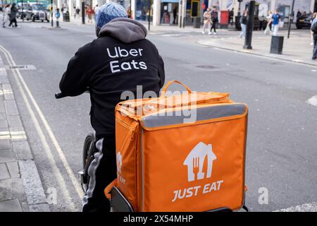 Just Eat / Uber Eats Take-away-Lieferzyklus Kurier am 7. April 2024 in London, Großbritannien. Just Eat Limited ist ein britischer Online-Service für die Bestellung und Lieferung von Lebensmitteln, der 2001 gegründet wurde . Sie fungiert als Vermittler zwischen unabhängigen Lebensmittelgeschäften und Kunden, wobei Tausende von Fahrradkurieren Lebensmittel per Fahrrad und anderen Transportmitteln liefern. Gig-Arbeitnehmer sind unabhängige Auftragnehmer, Online-Plattform-Mitarbeiter, Vertragsarbeiter, Bereitschaftsarbeiter und Leiharbeiter. Gig-Mitarbeiter schließen förmliche Vereinbarungen mit On-Demand-Unternehmen ab, um Dienstleistungen für die Kunden des Unternehmens zu erbringen. Stockfoto