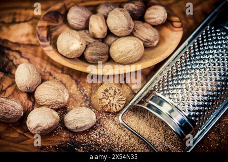 Muskatnuss, Muskatblüte (Myristica duftet), Muskatnuss auf einem Holzteller mit einem Holzlöffel, ganz und gerieben Stockfoto