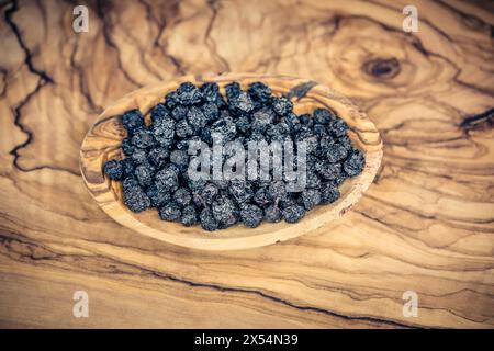 Schwarze Schokolade (Aronia melanocarpa, Photinia melanocarpa), Getrocknete Apfelbeeren auf einem Holzteller Stockfoto