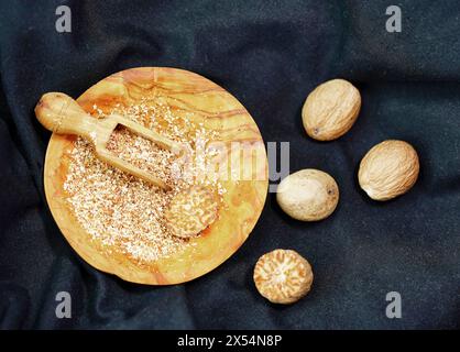 Muskatnuss, Muskatblüte (Myristica duftet), Muskatnuss auf einem Holzteller mit einem Holzlöffel. Ganz und gerieben Stockfoto