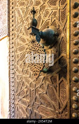 Ein detaillierter Bronzeklopfer ziert den Eingang von Cherratine Madrasa in Fès Medina. Stockfoto