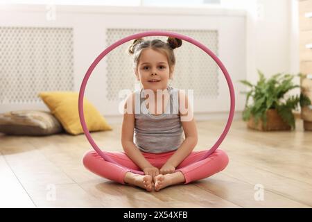 Kleines süßes Mädchen mit Hula Hoop auf dem Boden zu Hause. Übungen durchführen Stockfoto