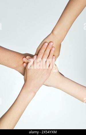 Nahaufnahme von Kindern, die ihre Hände vor grauem Hintergrund zusammenlegen. Freunde mit Handstapeln, die Einheit und Teamarbeit zeigen. Stockfoto