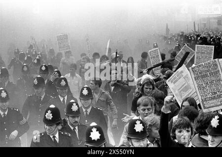 In der Schlacht von Lewisham explodieren Rauchbomben, während die Polizei die aufsässigen Anhänger der National Front beschützt, während sie während der so genannten Schlacht von Lewisham provokativ durch das New Cross marschieren. Einige tragen gedruckte Plakate: „Die nationale Front ist eine rassistische Front tritt der nationalen Front bei“. Lewisham, London, England 13. August 1977. HOMER SYKES AUS DEN 1970ER JAHREN Stockfoto