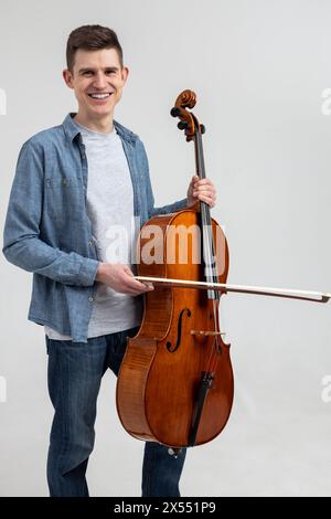 Junger Mann in lässiger Kleidung, der Cello spielt Stockfoto