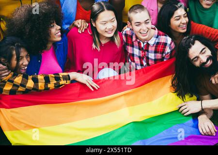 Verschiedene Menschen haben Spaß, die LGBT-Regenbogenfahne im Freien zu halten - multirassische Freunde haben Spaß zusammen nach dem Gay Pride Event Stockfoto
