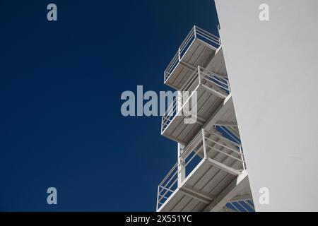 Modernes weißes Betongebäude mit einer Außentreppe aus Metall mit blauem Himmel Stockfoto
