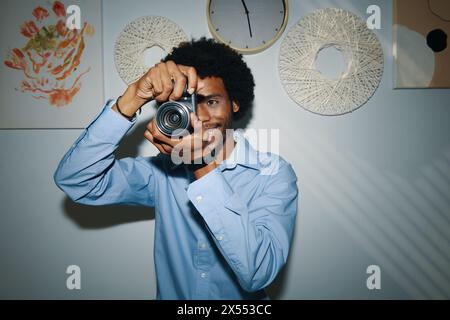Talentierter, lächelnder Schwarzer Mann, der Fotos macht Stockfoto