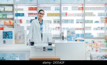 Apotheke Drugstore: Porträt des schönen kaukasischen Apothekers, der hinter der Kasse steht, charmant lächelt und in die Kamera blickt. Moderne Apotheke mit Regalen voller Medizinpakete Stockfoto