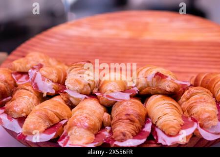 Frisch gebackene Croissants mit köstlichen Marmeladen auf verschwommenem Holzbrett Hintergrund Stockfoto