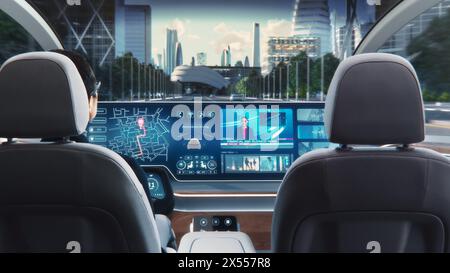 Futuristisches Konzept: Eleganter Geschäftsmann, der die Navigations-App auf einem Augmented Reality Dashboard mit Finanznachrichten nutzt, während er in einem autonomen, selbstfahrenden emissionsfreien Elektroauto sitzt. Stockfoto