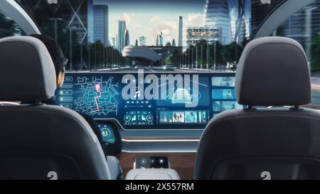 Futuristisches Konzept: Eleganter Geschäftsmann, der die Navigations-App auf einem Augmented Reality Dashboard mit Finanznachrichten nutzt, während er in einem autonomen, selbstfahrenden emissionsfreien Elektroauto sitzt. Stockfoto