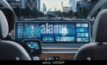 Futuristisches Konzept: Eleganter Geschäftsmann, der die Navigations-App auf einem Augmented Reality Dashboard mit Finanznachrichten nutzt, während er in einem autonomen, selbstfahrenden emissionsfreien Elektroauto sitzt. Stockfoto