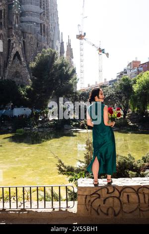 Eine Frau posiert mit einem Strauß roter Rosen auf einem Mäuerchen vor der Sagrada Familia in Barcelona, Spanien redaktionelle Verwendung nur Barcelona Kataloni Stockfoto