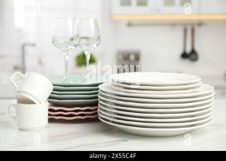 Saubere Teller, Tassen und Gläser auf weißem Marmortisch in der Küche Stockfoto