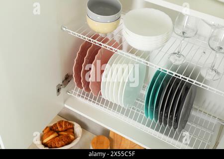 Reinigen Sie Teller, Schüsseln und Gläser auf den Regalen im Schrank im Innenbereich Stockfoto