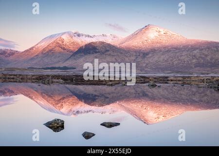 Sonnenlicht auf dem schneebedeckten Black Mount, reflektiert in Lochan na h-Achlaise auf Rannoch Moor, Schottland. (März) 2024. Stockfoto