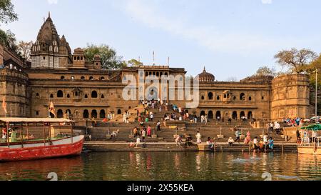 Blick auf Mahareshwa Ghats und Tempel vom Fluss narmada aus, der mit Pilgern und Besuchern auf den Stufen beschäftigt ist Stockfoto