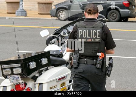 Washington DC, USA - 1. Mai 2024: Polizeibeamter der Polizeieinheit steht neben einem Motorrad, das auf einer Straße in Washington DC geparkt ist Stockfoto