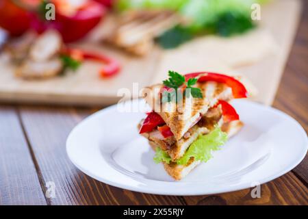 Gebratener Toast mit Huhn, Salat, Gemüse auf einem Holztisch. Stockfoto