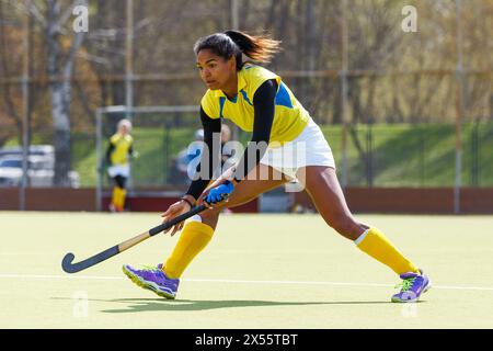 Junge schwarze Feldhockeyspielerin, die auf dem Spielfeld in Verteidigungsposition steht Stockfoto