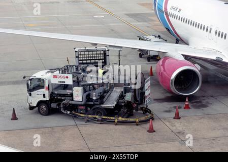 Kapstadt, Südafrika. 30. April 2024. Tankwagen, der ein Passagierflugzeug auf dem Flughafenvorfeld über ein Rohr unter dem Flügel betankt Stockfoto