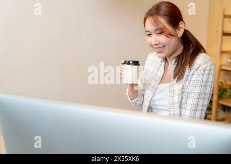 Die junge Frau arbeitet und trinkt zu Hause Kaffee Stockfoto