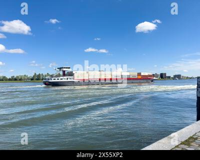 Dordrecht, Niederlande - 29. April 2024: Binnenschiffsfrachttransport, der an Dordrecht vorbei an der Maas fährt. Containerschifftransport Stockfoto