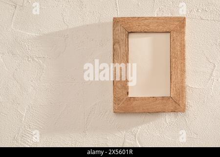 Einfacher Bilderrahmen aus Holz, montiert auf einer strukturierten Steinwand Stockfoto