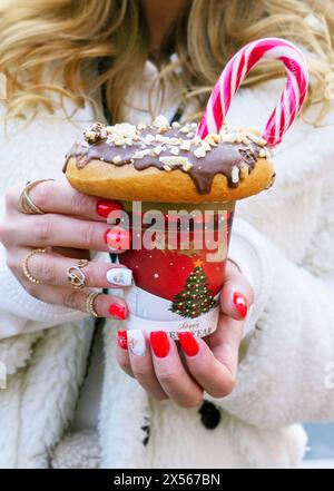 Mädchen, das einen Milchshake mit Donuts und anderen Süßigkeiten in einem Glas hält Stockfoto