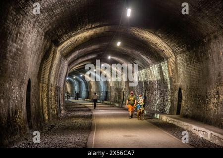 Die Menschen laufen durch den Grabstein Tunnel auf dem Monsal Trail, der durch den Hügel am Monsal Head im Derbyshire Peak District England führt Stockfoto