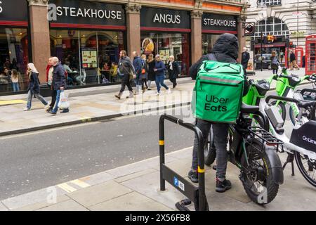 Uber isst Essenskurier vor einem Angus Steakhouse in Zentral-London. Stockfoto