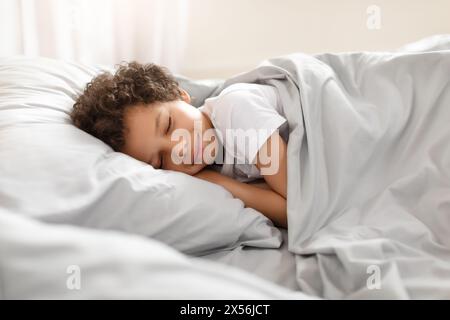 Junger afroamerikanischer Junge, der im Bett schläft Stockfoto