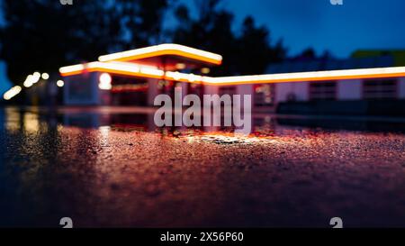 Alte schöne beleuchtete Tankstelle in einer regnerischen Nacht verschwommen im Hintergrund Stockfoto