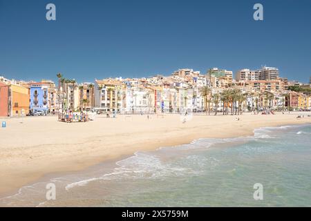 Blick auf die wunderschöne Küstenstadt Villajoyosa. Strandpromenade mit farbenfrohen Häusern, Leute, die sich in Cafés im Freien und am Strand an sonnigen Tagen in La Vil entspannen Stockfoto