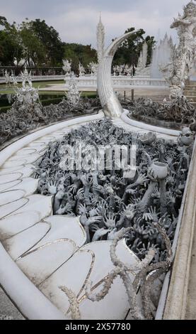 Skulpturen von Händen und Gesichtern, die nach oben am Weißen Tempel, Wat Rong Khun, in der Provinz Chiang Rai in Thailand reichen Stockfoto