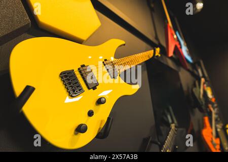 Moderne gelbe E-Gitarre hängt an der Wand mit anderen, Gitarrenladen. Hochwertige Fotos Stockfoto