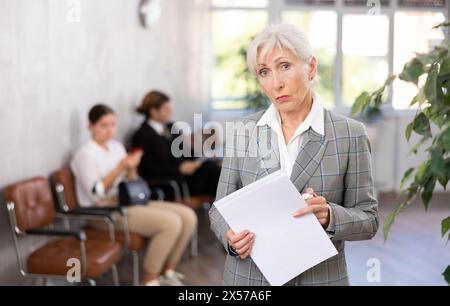 Porträt einer enttäuschten älteren Geschäftsfrau, die Papierdokumente in den Händen hält Stockfoto