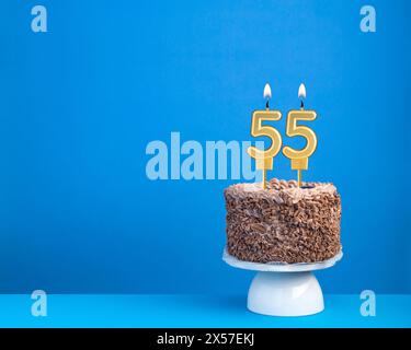 Geburtstagsfeier mit Kerze 55 - Schokoladenkuchen auf blauem Hintergrund Stockfoto