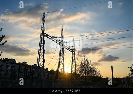 Elektrische Pole und Stromleitungen bei Sonnenuntergang. Übertragung elektrischer Energie. Hochspannungs-Pylonturm und Stromleitungen. Elektrische Leistungsstatio Stockfoto