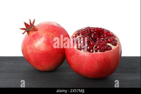 Frische Granatäpfel auf schwarzem Holztisch vor weißem Hintergrund Stockfoto