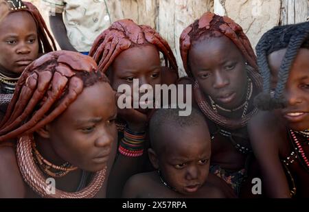 Eine Gruppe von Himba-Kindern und jungen Frauen sehen sich Bilder mit einer Kamera an, in der Nähe von Opuwo, Kaokoveld, Kunene, Namibia Stockfoto