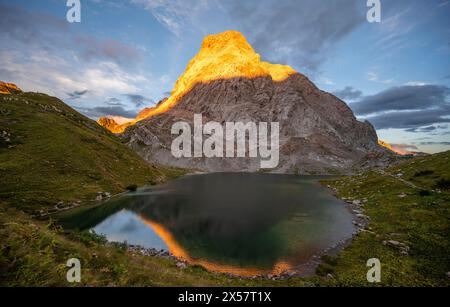 Alpenglow am Seekopf oder Monte Capolago, Reflexion am Wolayersee, Berglandschaft mit grünen Wiesen und Bergsee bei Sonnenuntergang, Karnische Alpen Stockfoto