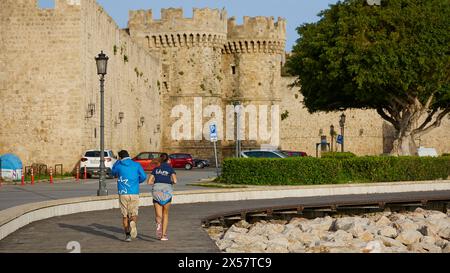 Jogger bewegen sich entlang einer Straße mit Blick auf historische Burgmauern und einen einzigen Baum, Seetor, Hafenviertel, Rhodos-Stadt, Rhodos, Dodekanesisch, Griechisch Stockfoto