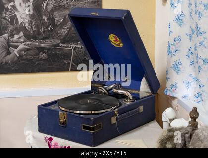 NARYM, RUSSLAND - 32. JULI 2023. Ein Grammophon der Mitte des 20. Jahrhunderts auf dem Hintergrund einer Fotografie, die während des Zweiten Weltkriegs aufgenommen wurde Stockfoto